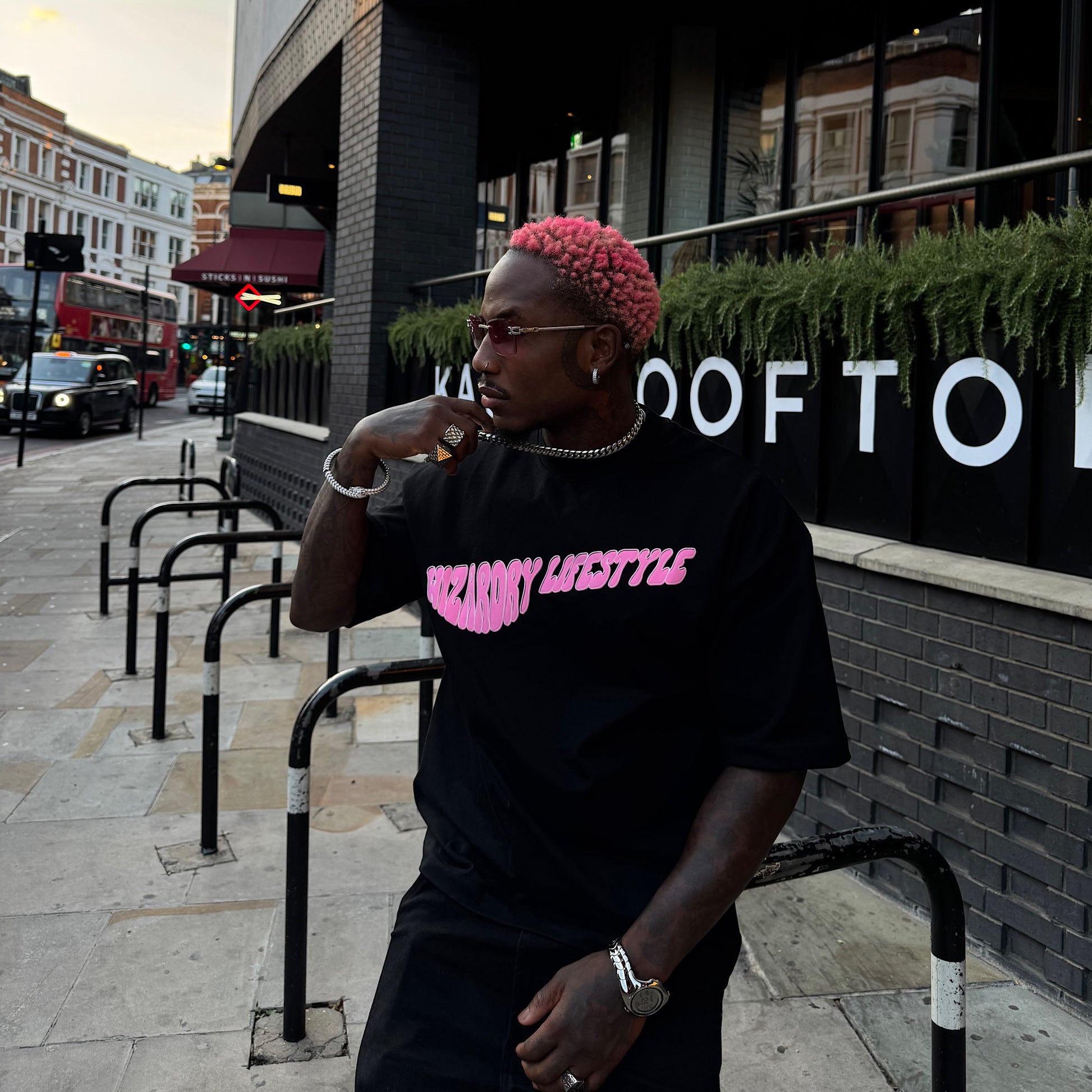 Model wearing the Wizardry Lifestyle oversized heavyweight black graphic T-shirt featuring the pink ‘Lifestyle’ chest print